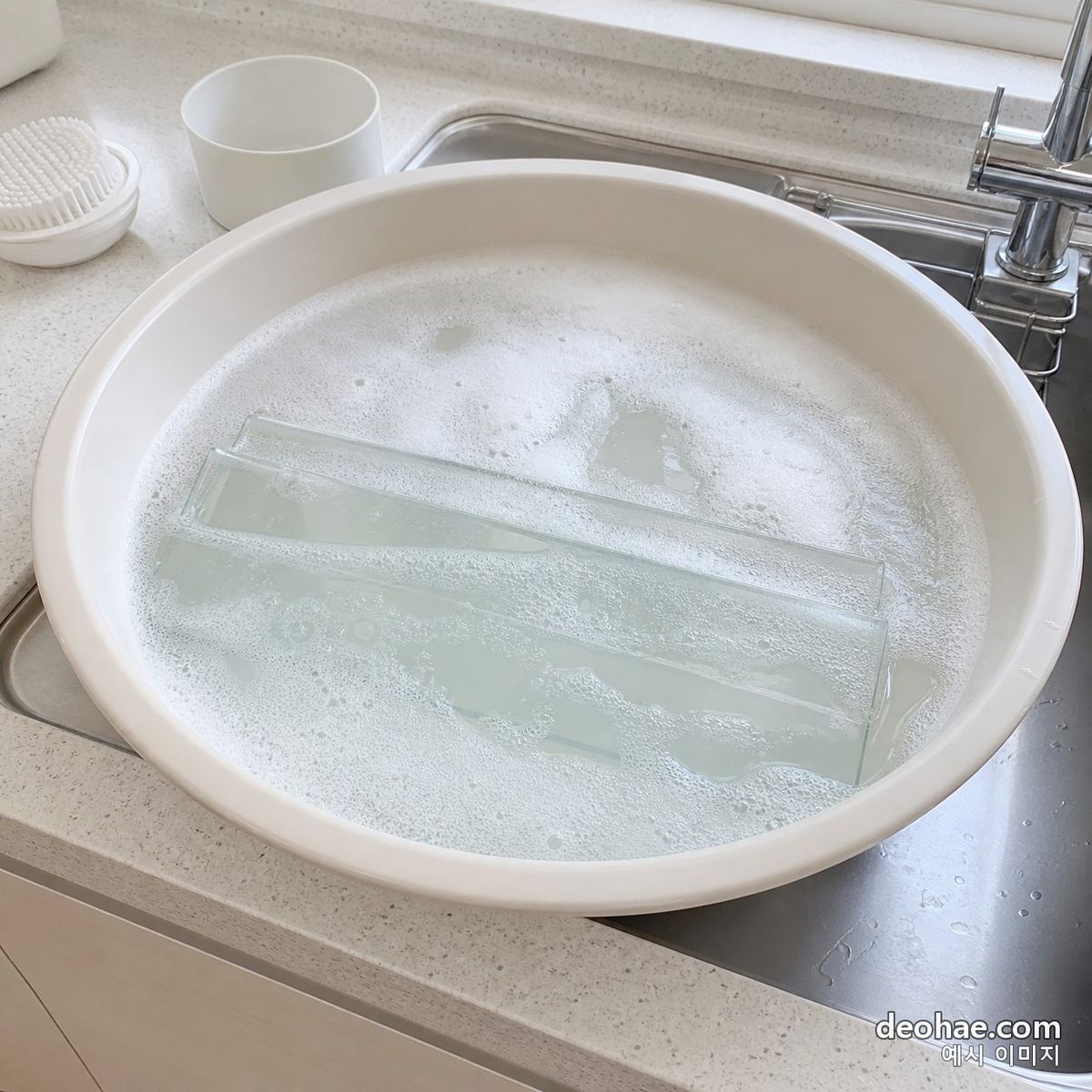 분리한 선반을 미온수와 세제에 담가 불리는 장면