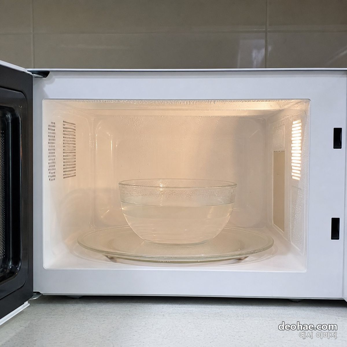 물과 식초를 담은 내열 그릇을 전자레인지에 넣는 장면